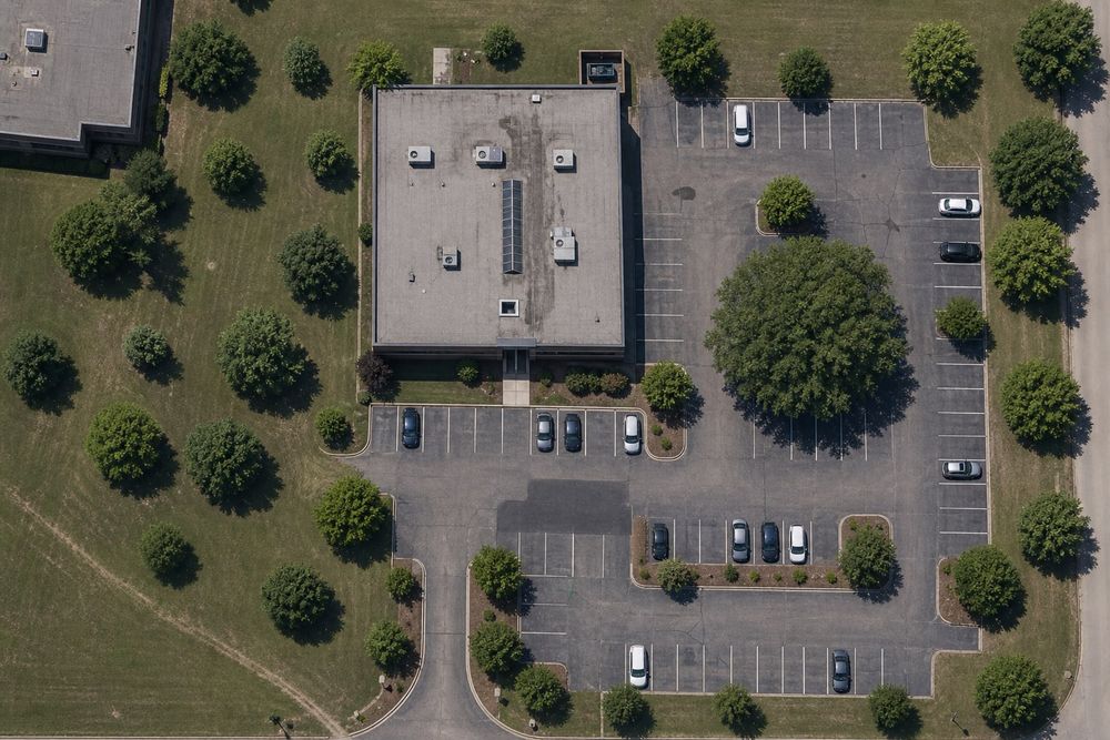 Aerial view of an office building with parking lot trees and lawn